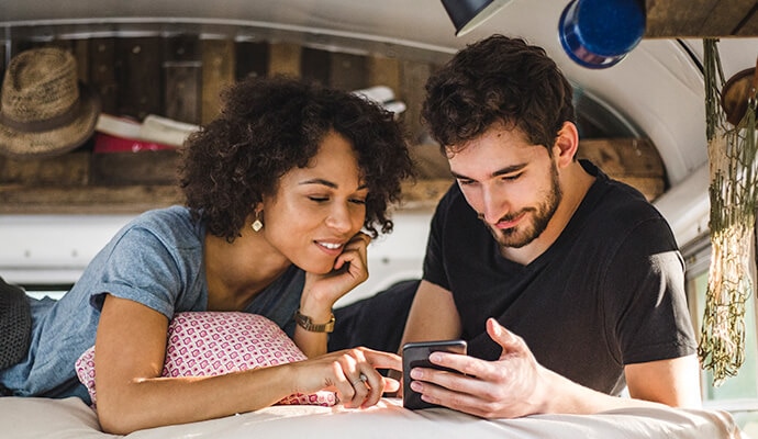 мужчина за столом смотрит в свой телефон с Norton 360 Standard.